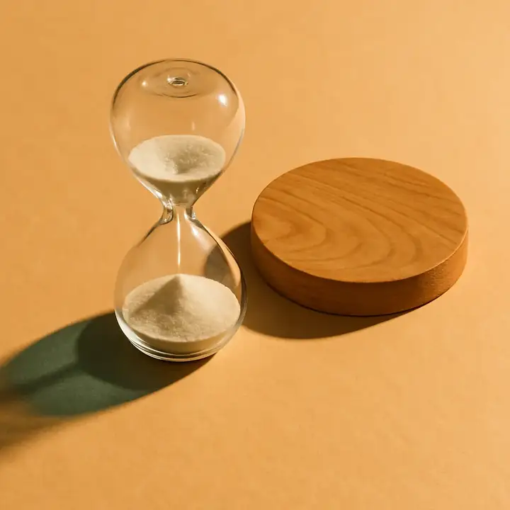 Hourglass and a wooden disc on warm paper